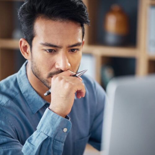 Serious, business man and thinking on computer in office, internet research and website. Focused ma.